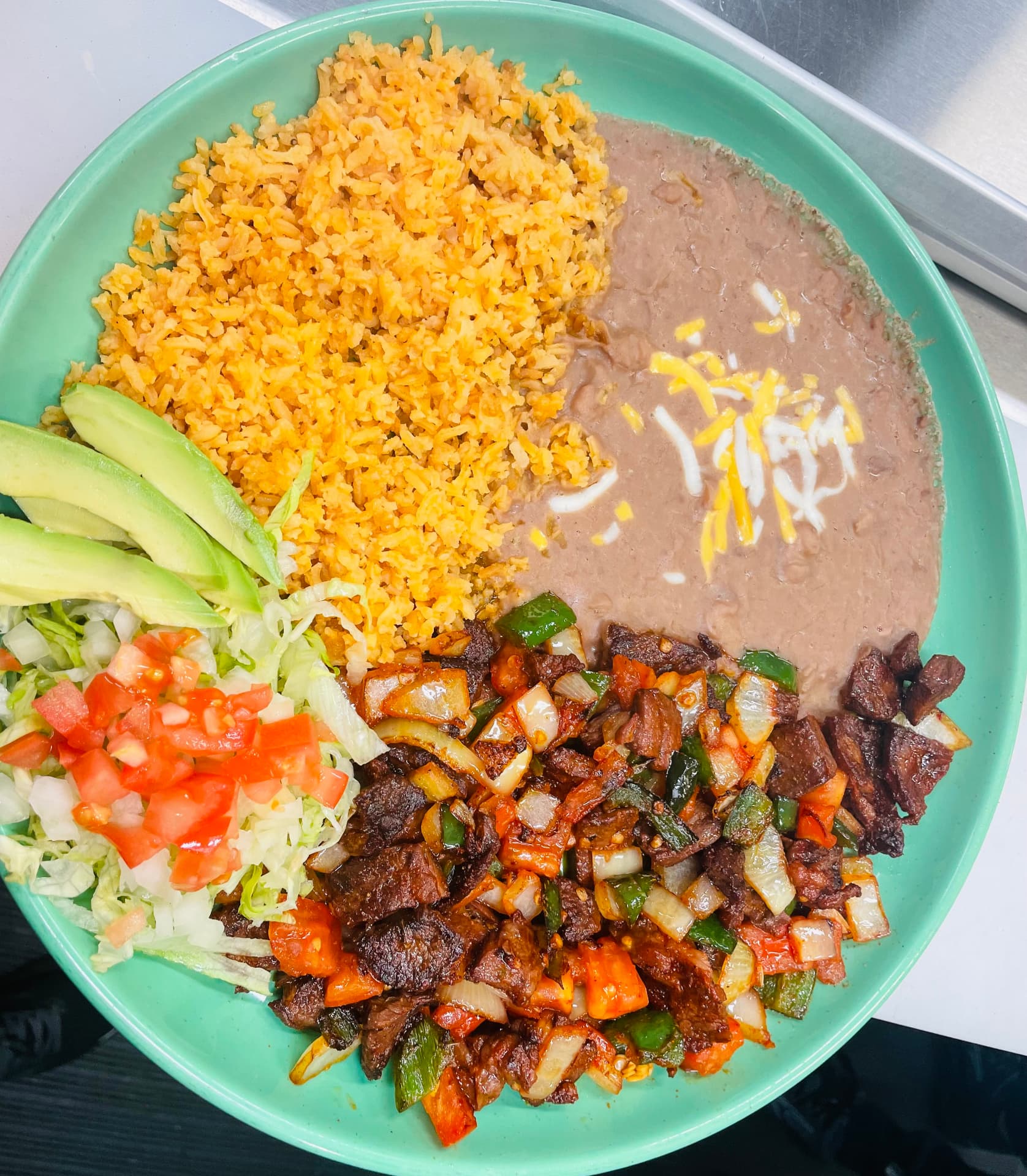 Bistec a la mexicana with peppers, onion and tomato, served with rice, beans and avocado