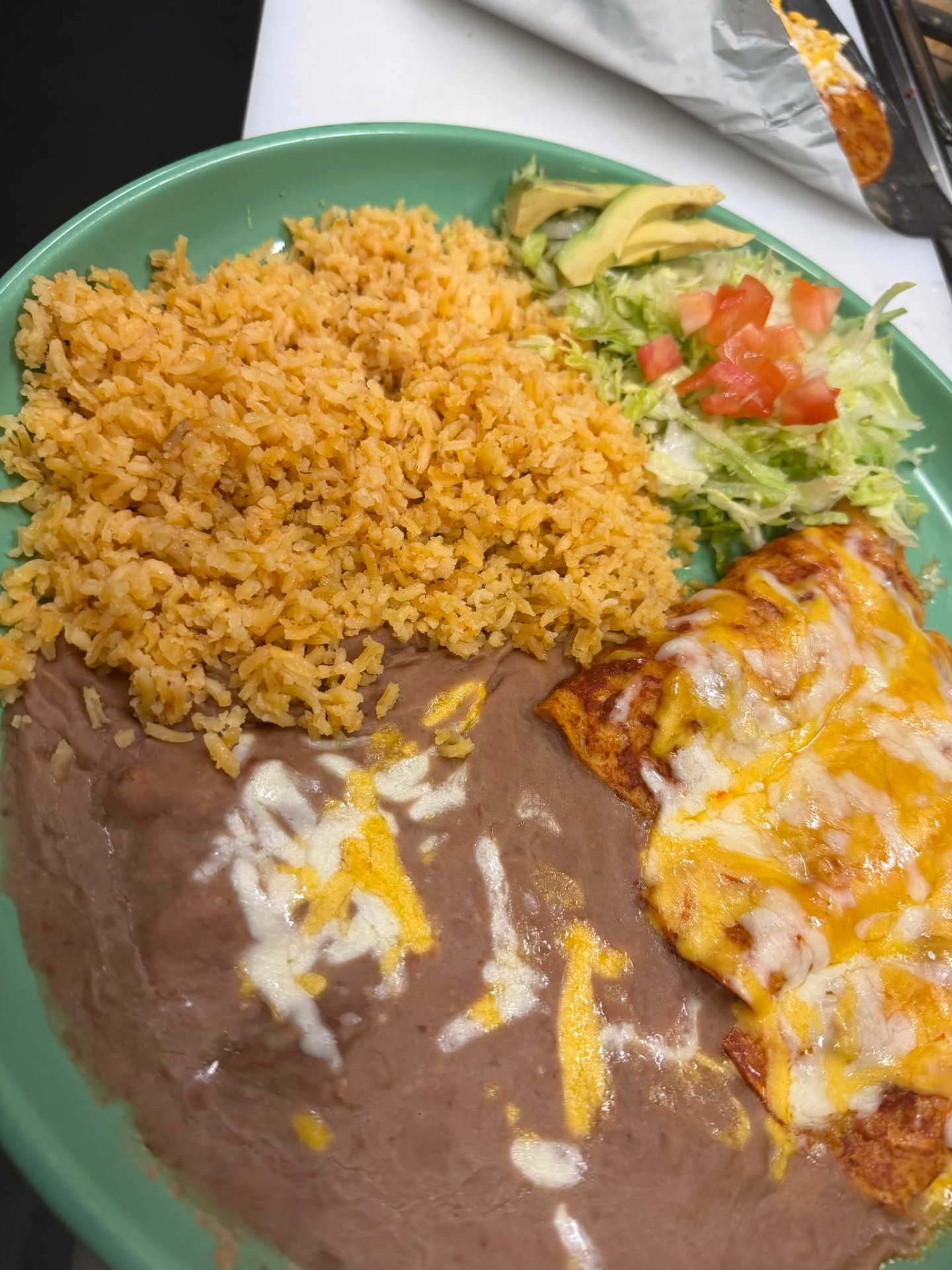 Cheese-topped enchiladas with Mexican rice, refried beans and salad