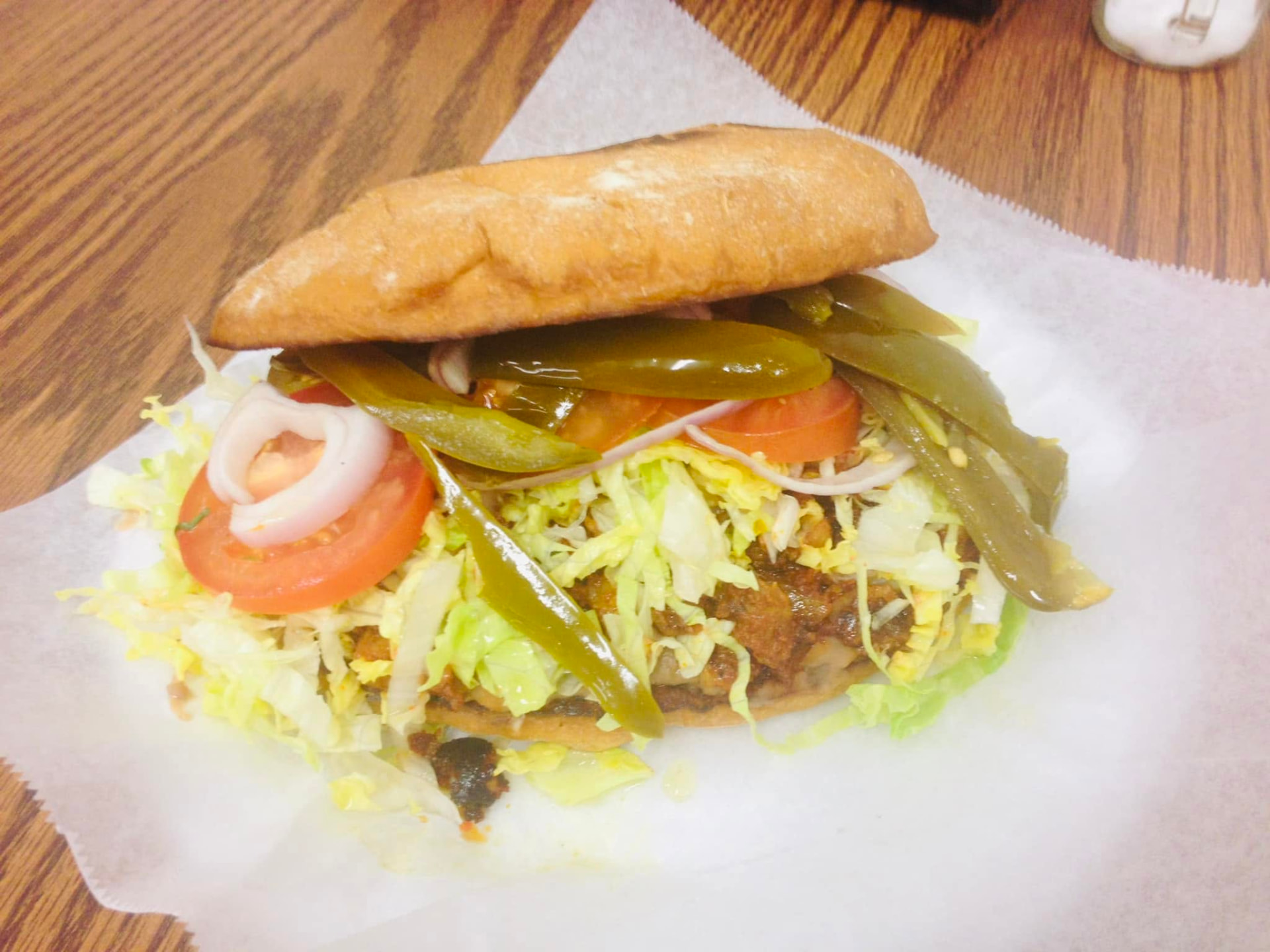 Torta on grilled bread with meat, lettuce, tomato, onion and pickled jalapeño