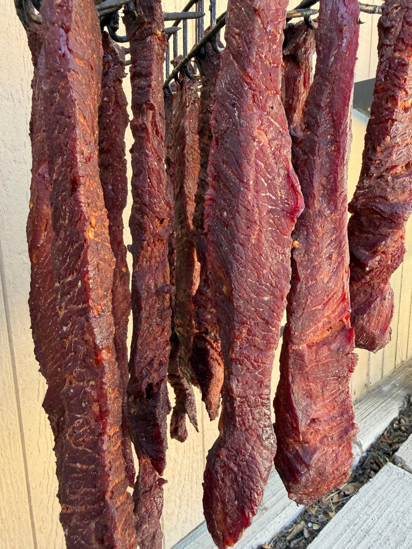 Strips of marinated beef jerky curing in the sun