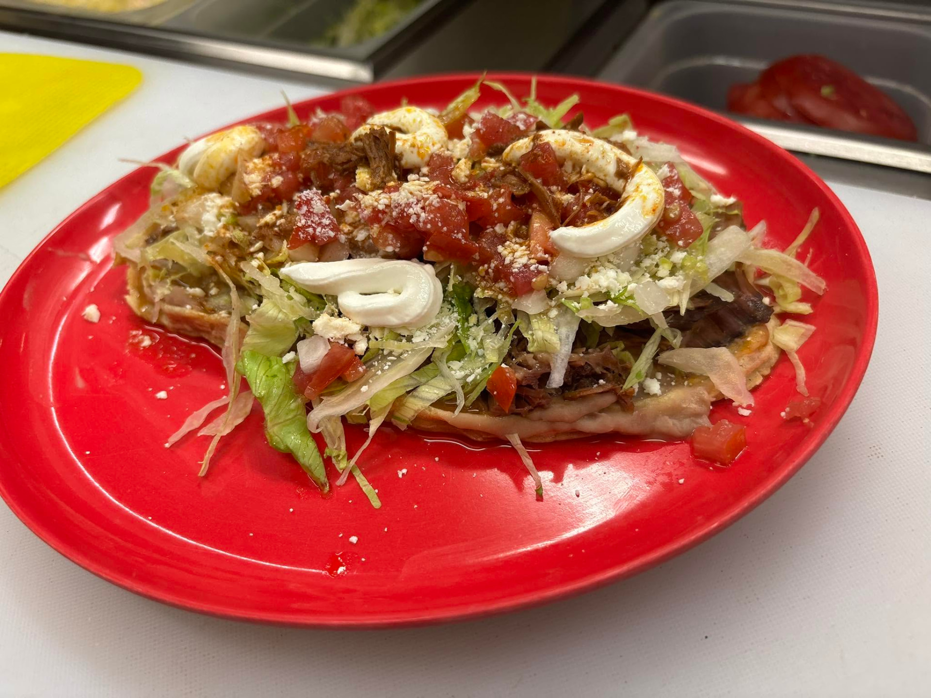 Sope topped with beans, meat, lettuce, pico de gallo, crema and queso fresco