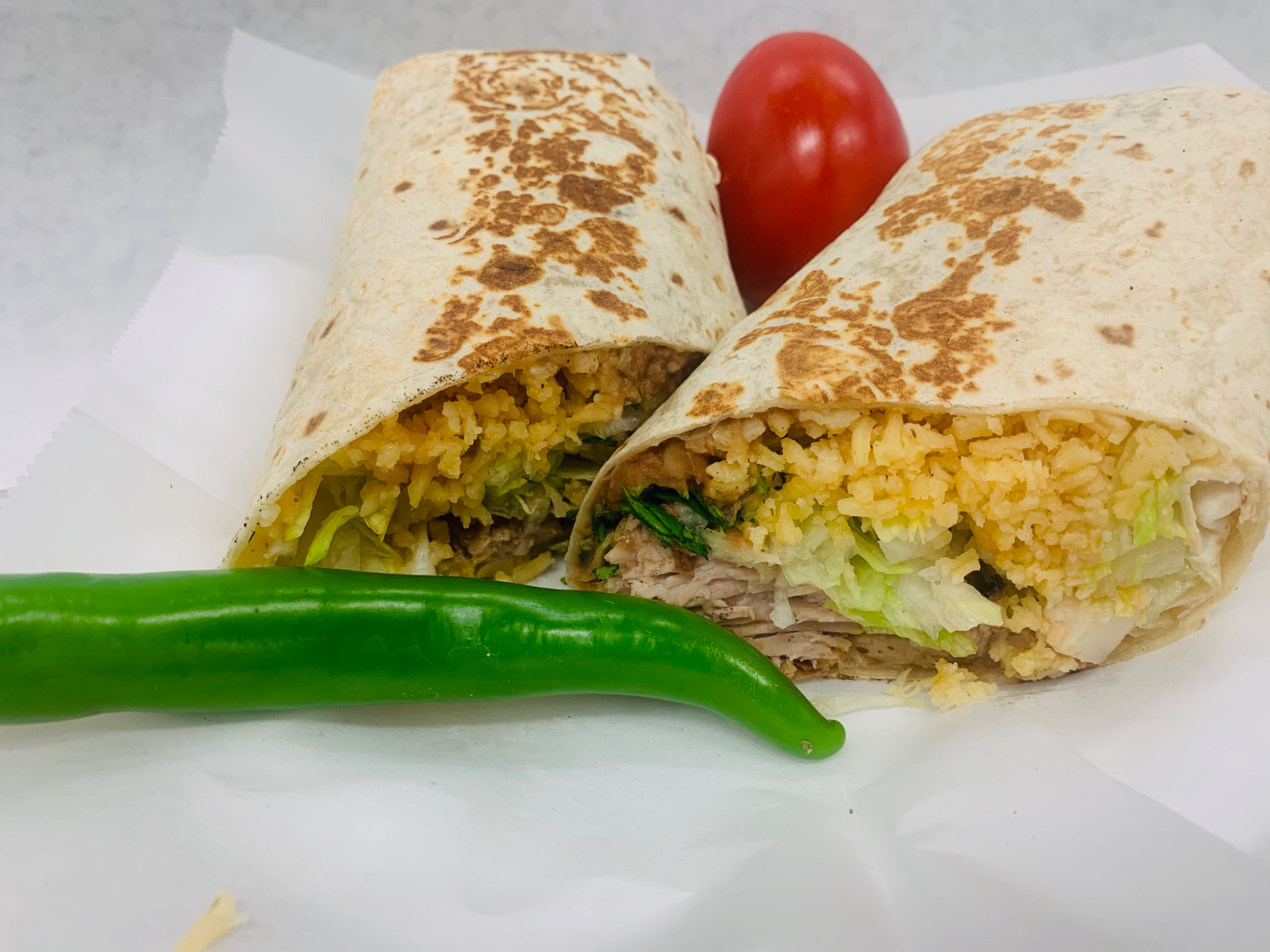 Burrito cut in half showing meat, rice, beans and lettuce