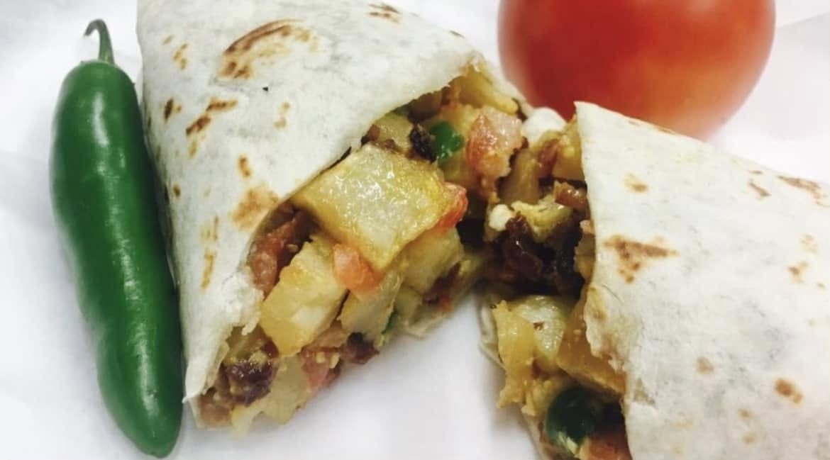 Breakfast burrito with bacon, egg and potato cut in half at Jake's Meats