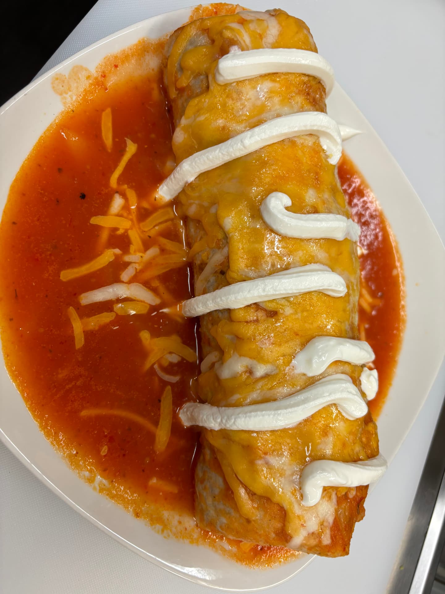 Burrito mojado smothered in red sauce, melted cheese and crema at Jake's Meats