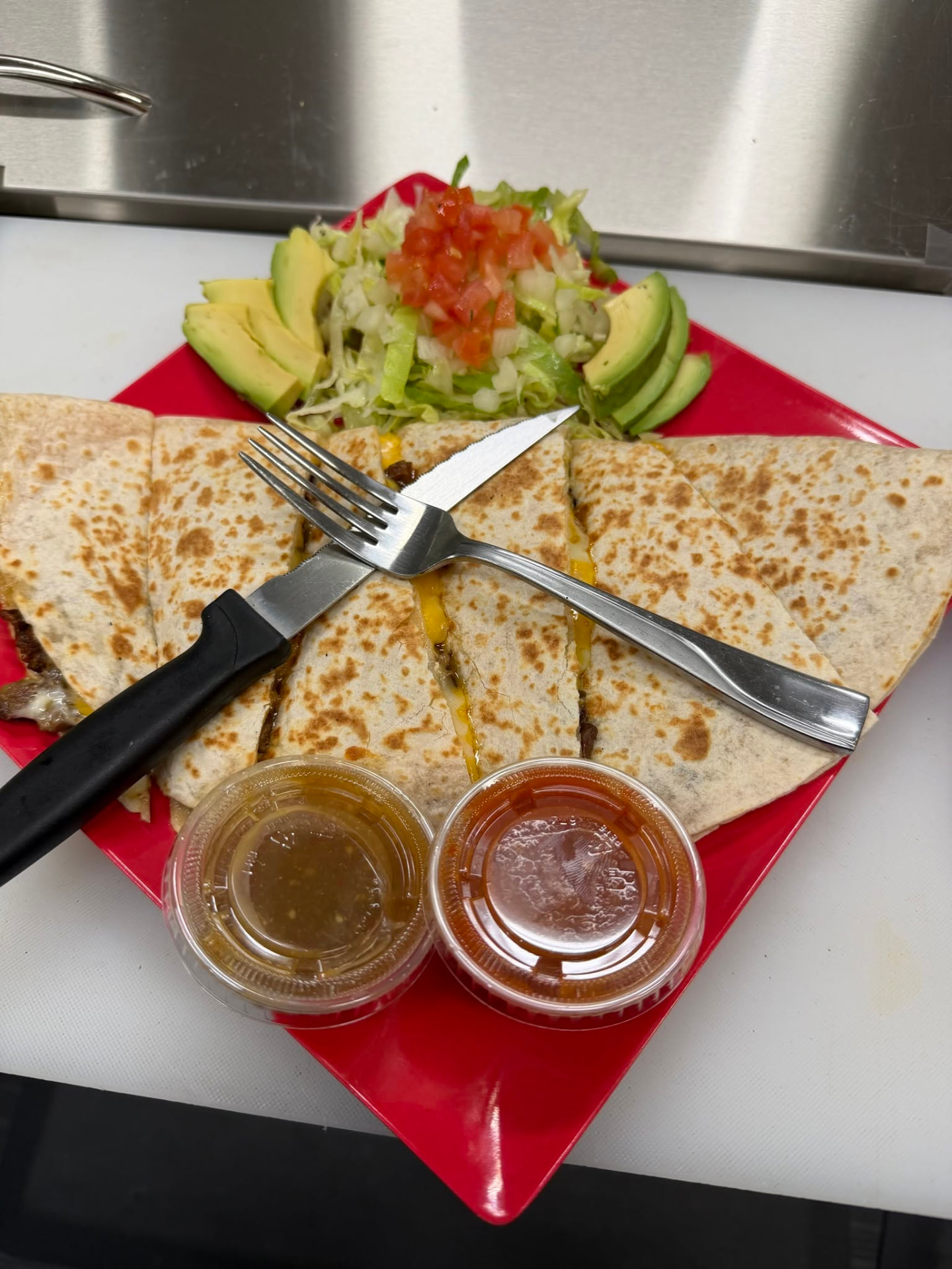 Grilled quesadilla with melted cheese, meat, avocado, salad, and salsa at Jake's Meats